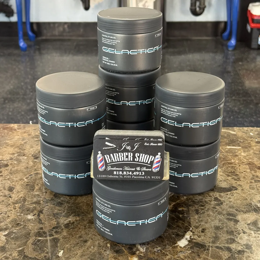 Jars of Gelactica control styling gel stacked on the counter with J&J business cards